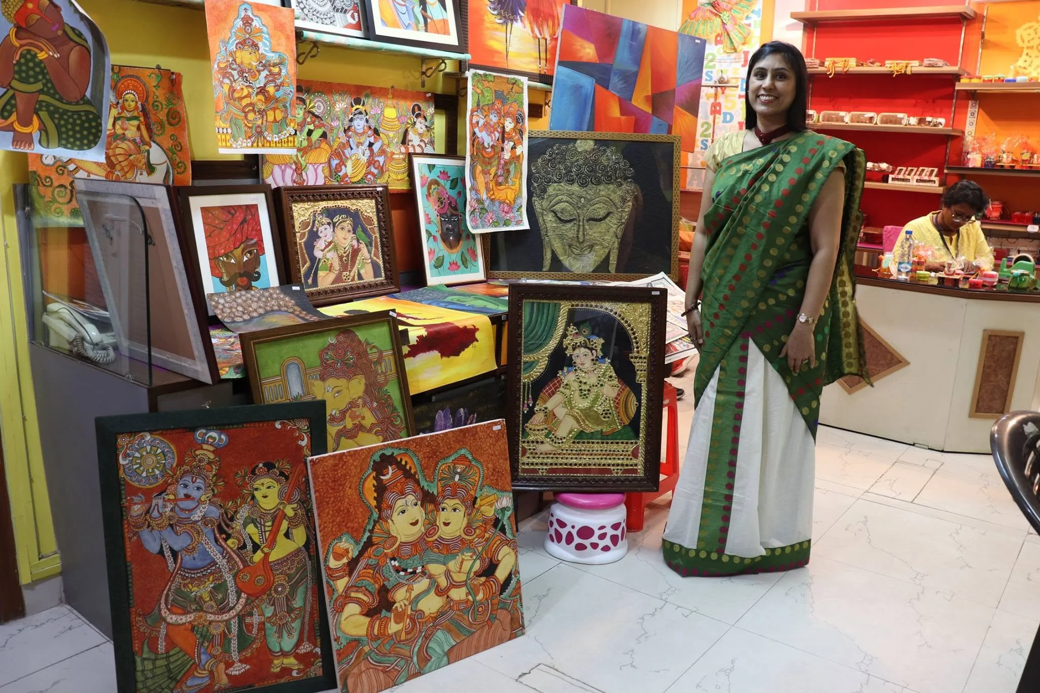 A woman standing beside a colourful display of her artwork