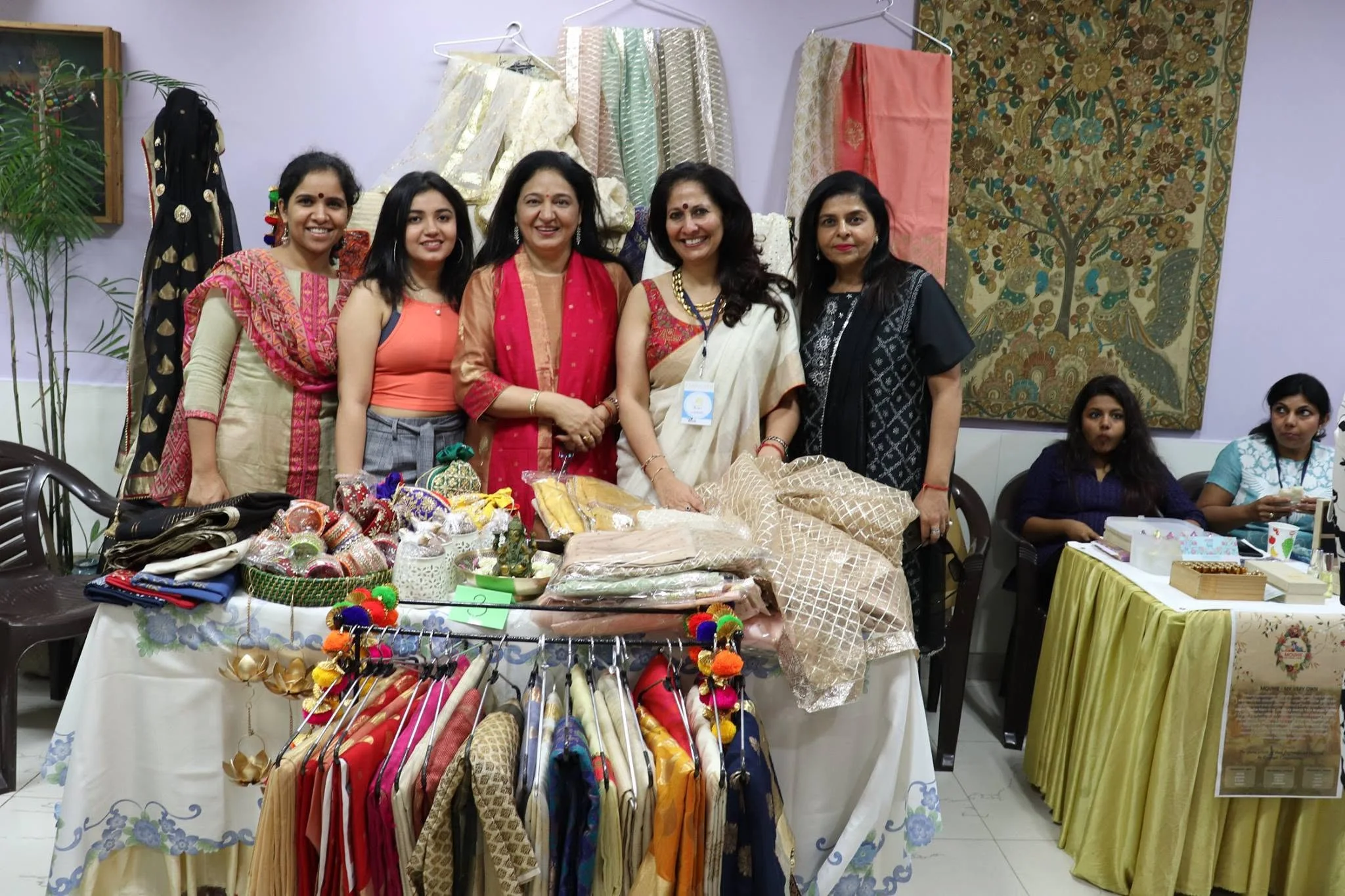 Women smiling behind a clothing and craft stall