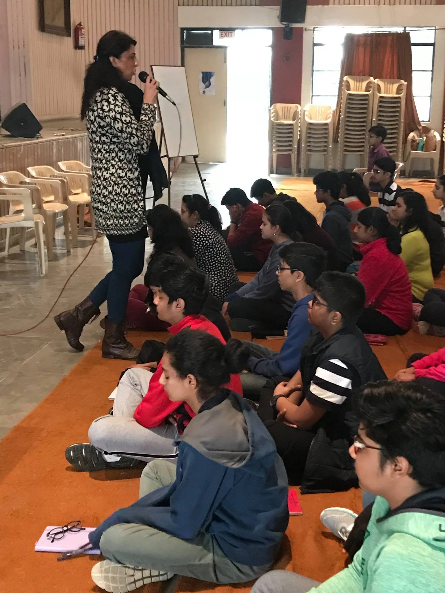 Vibha Gurtu speaking into a microphone before children